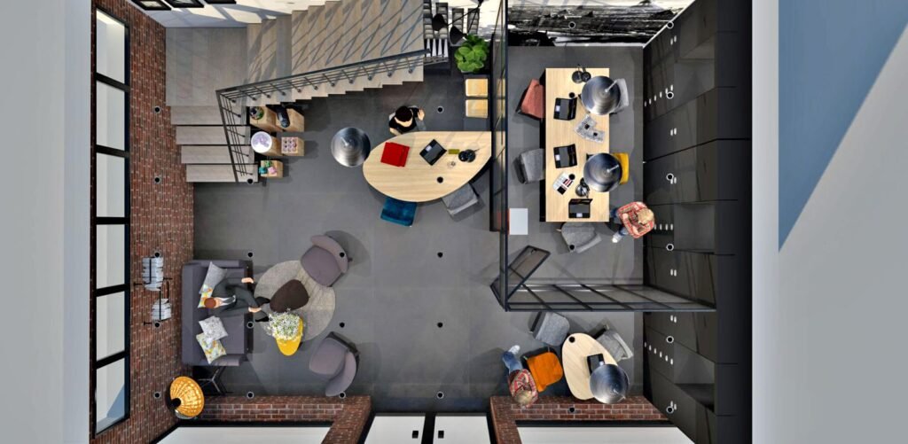 Vue de haut en bas d'un bureau moderne avec des bureaux, des chaises, des ordinateurs, un coin canapé et un escalier ; des murs en briques et de grandes fenêtres sont visibles.