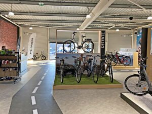 Une variété de vélos est exposée dans un magasin, y compris des vélos électriques et des vélos de ville.