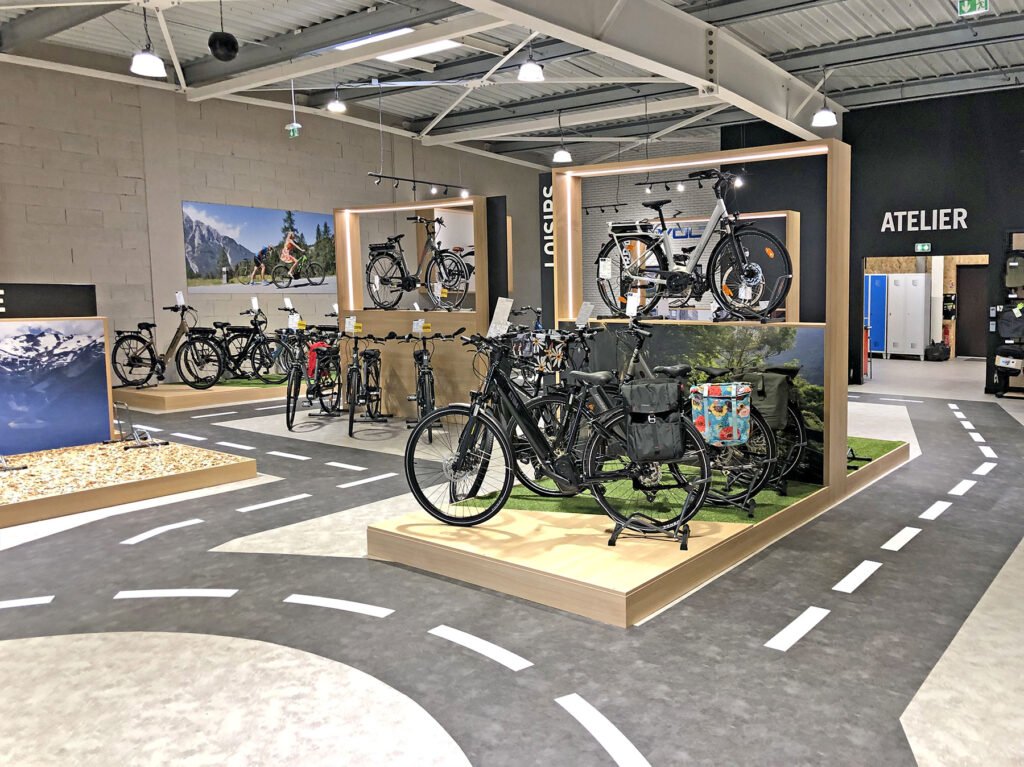 Une exposition intérieure de différents vélos avec un sol sur le thème de la route.