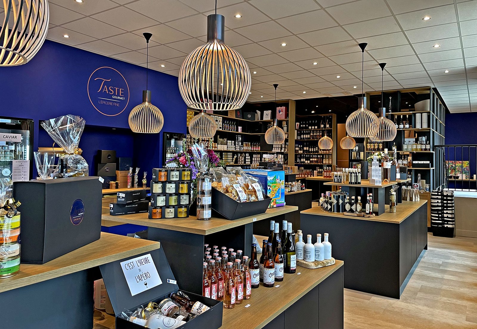 Intérieur d'un magasin de produits gastronomiques avec des étagères remplies de vin, de bocaux et de coffrets cadeaux.