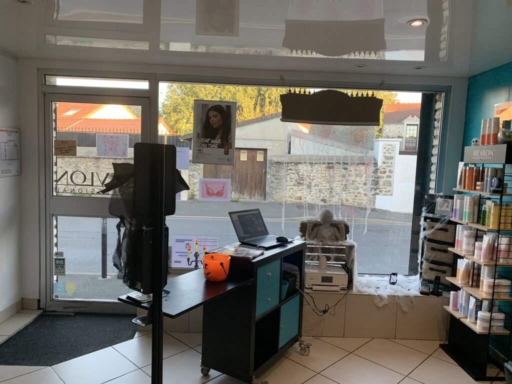Réception d'un salon décorée pour Halloween avec un seau en forme de lanterne sur le comptoir, des étagères de produits sur la droite et une vue de la rue à travers la fenêtre principale.