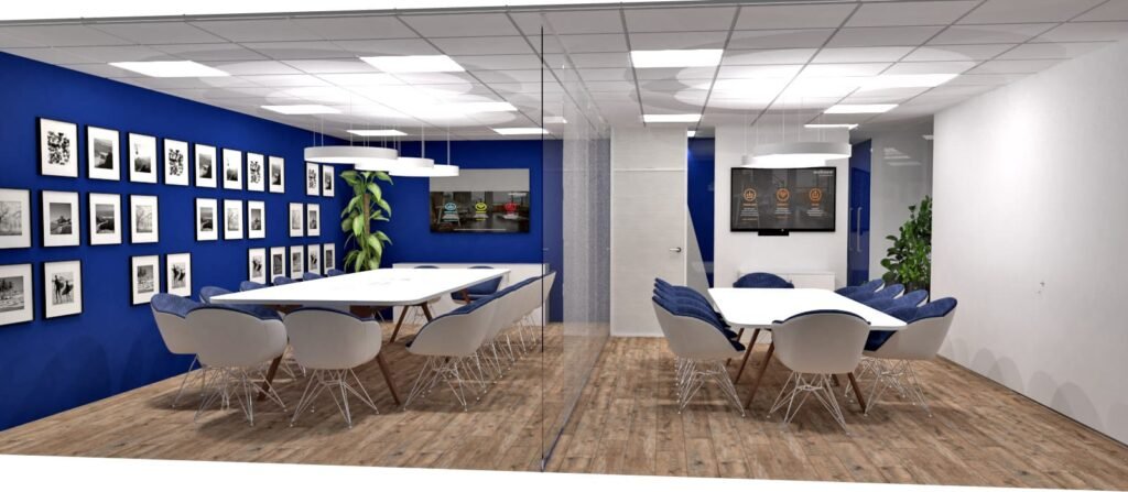 Salle de conférence moderne avec deux longues tables blanches, un mur d'accent bleu avec des photos encadrées, des chaises bleues, des lampes suspendues et des écrans muraux. Le sol est en bois et des plantes sont présentes.