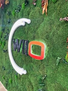 Un mur de mousse verte avec le mot "WILD" en grandes lettres, avec un "D" rougeoyant et des feuilles et plantes environnantes en guise de décoration.