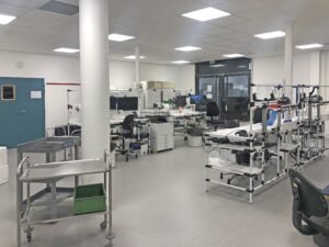 Un laboratoire propre et moderne avec des postes de travail, du matériel de laboratoire, des ordinateurs, des chariots roulants et diverses fournitures organisées dans la pièce.