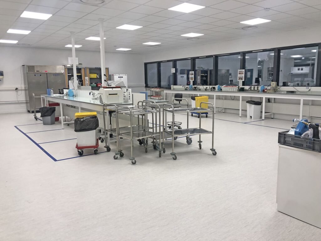 Un laboratoire propre et moderne avec des postes de travail, du matériel de laboratoire et des chariots, doté de grandes fenêtres et d'un éclairage fluorescent.