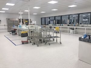 Un laboratoire propre et moderne avec des postes de travail, du matériel de laboratoire et des chariots, doté de grandes fenêtres et d'un éclairage fluorescent.