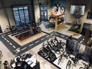 Une salle d'exposition avec plusieurs présentoirs à vélos, des vélos accrochés aux murs et une personne travaillant à un bureau près d'accessoires pour vélos.