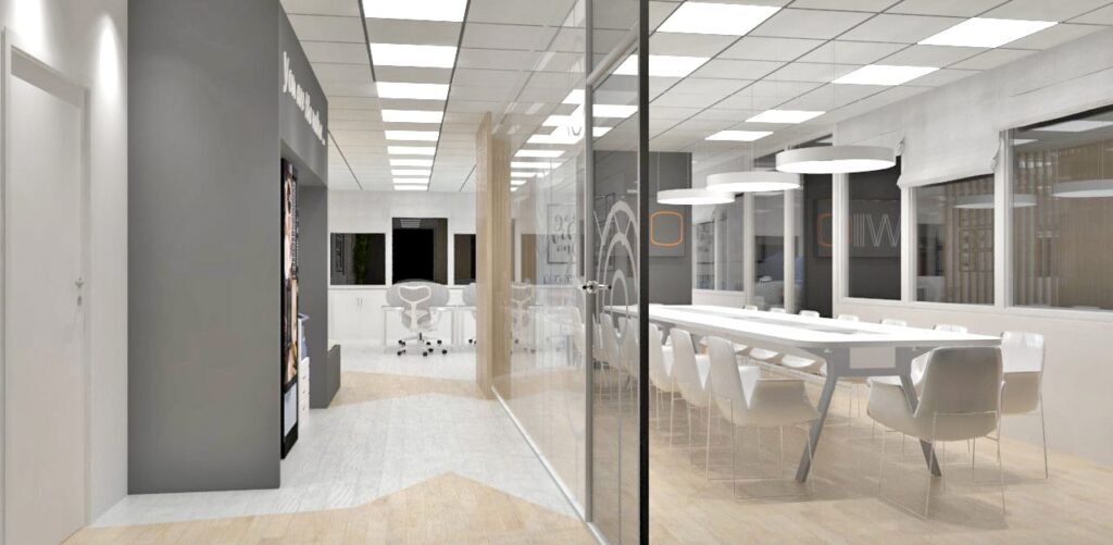 Espace de bureau moderne avec une salle de conférence vitrée, des tables et des chaises blanches, un éclairage zénithal et de grandes fenêtres.