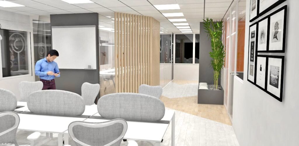 Salle de réunion d'un bureau moderne avec des chaises grises, une longue table, des œuvres d'art murales, une plante en pot et un homme debout près d'un tableau blanc en train de regarder son téléphone.