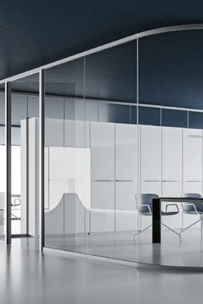 Intérieur de bureau moderne avec des murs en verre, un mobilier blanc minimaliste, une table de réunion rectangulaire et plusieurs chaises sur un sol épuré de couleur claire.