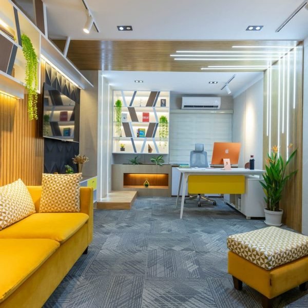 a yellow couch sitting in a living room next to a desk